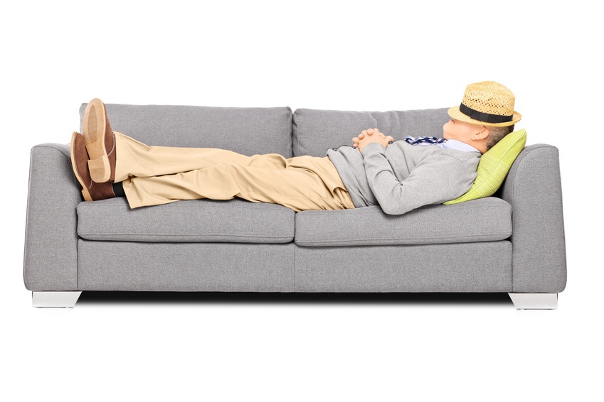 Mature man with hat over his head sleeping on a sofa isolated on white background